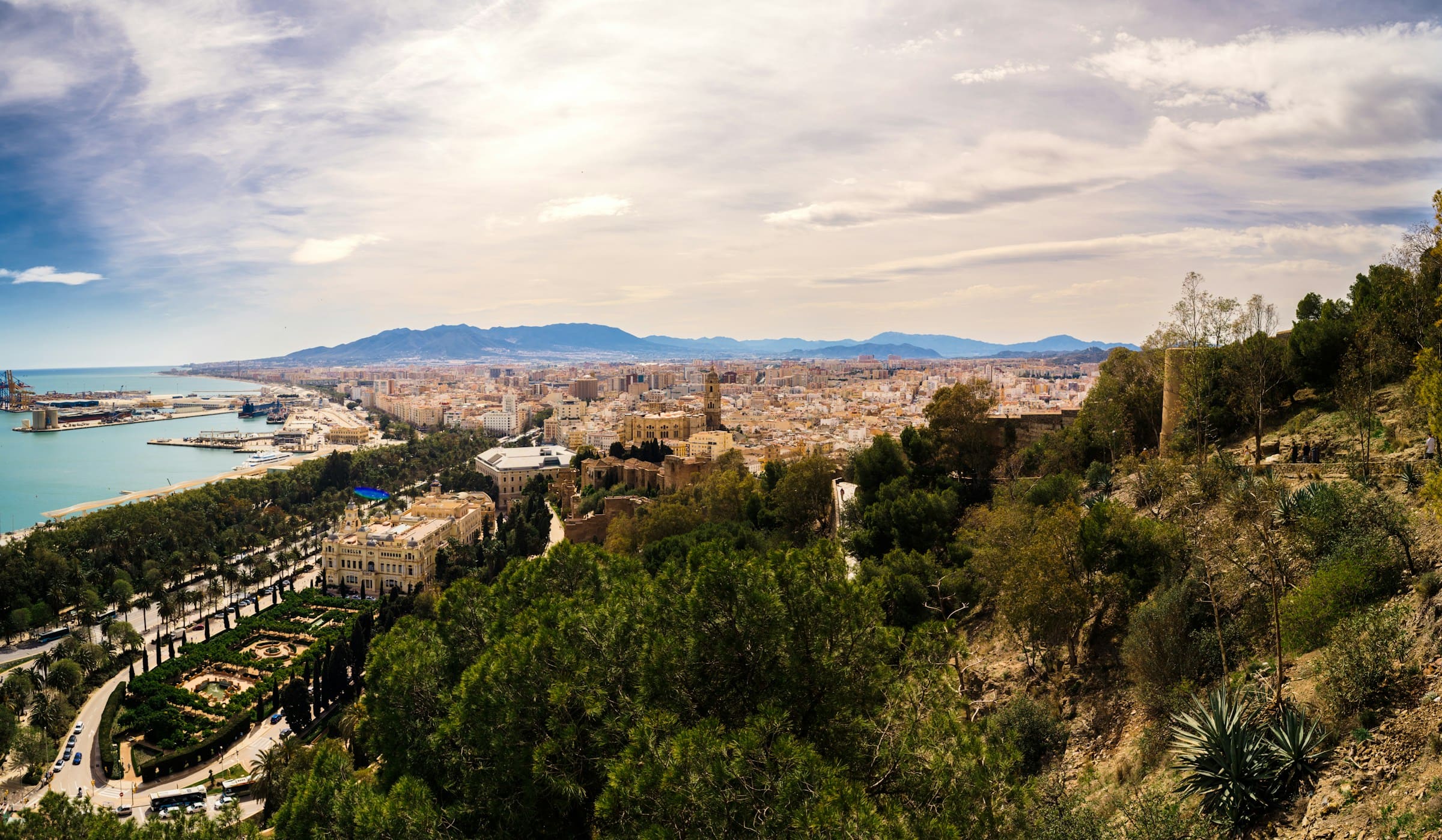 The Costa del Sol from the hills above Malaga: the old town and the port below, the bay beyond and the sierra behind it.