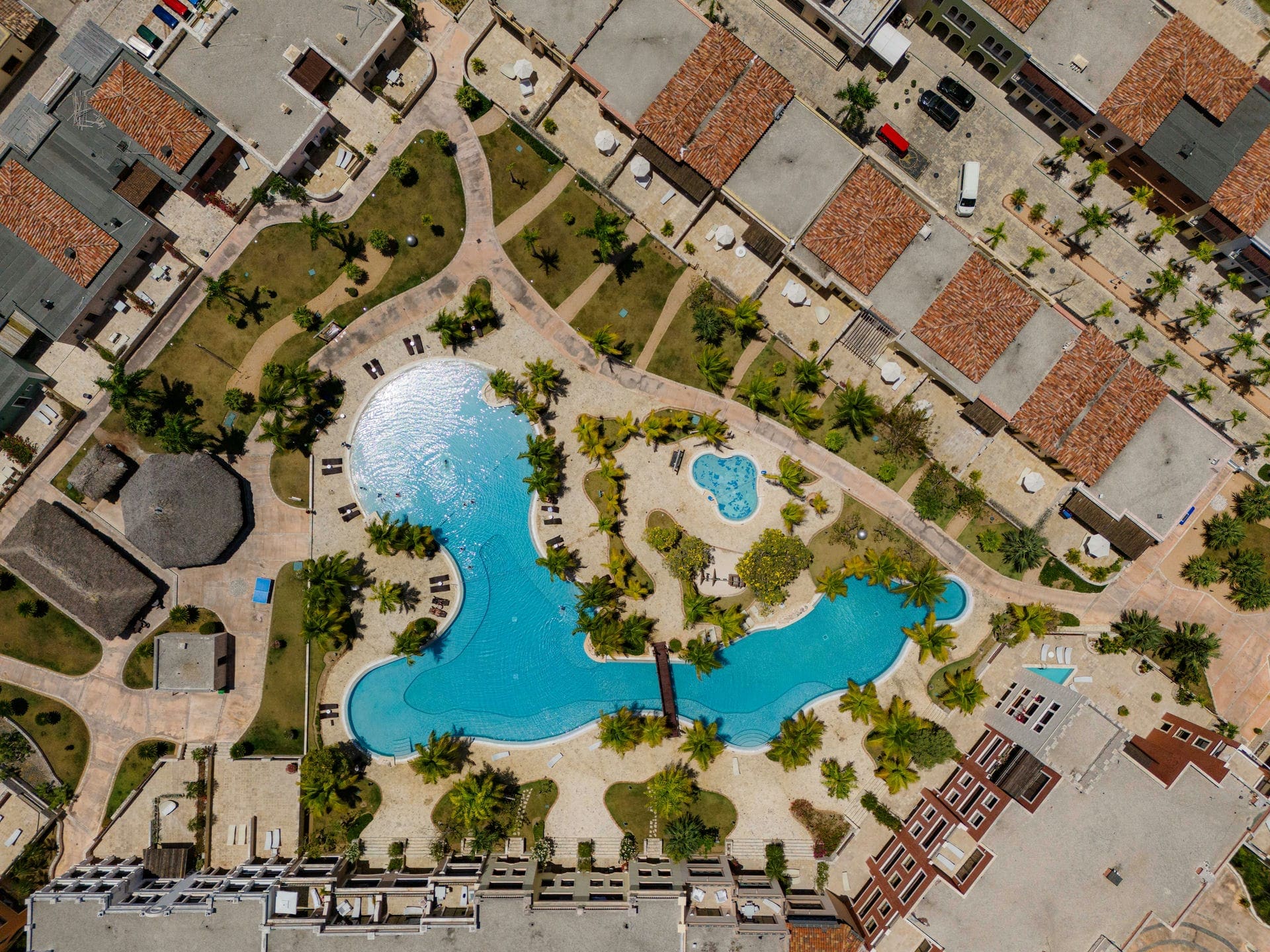 A large freeform leisure pool in Cap Cana seen from directly above, with sun terraces and palms around it.