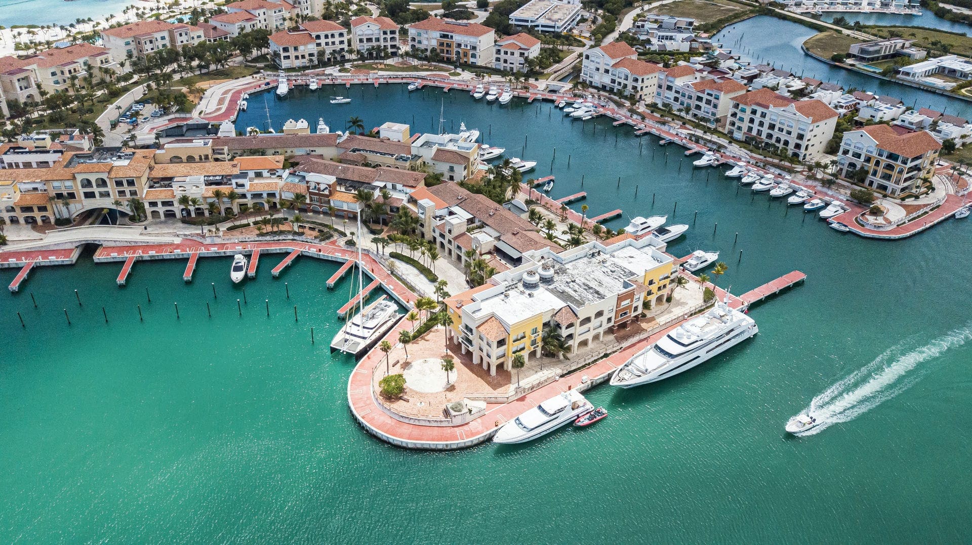 Marina Cap Cana from the air, yachts along the quays with the marina village around the basin.