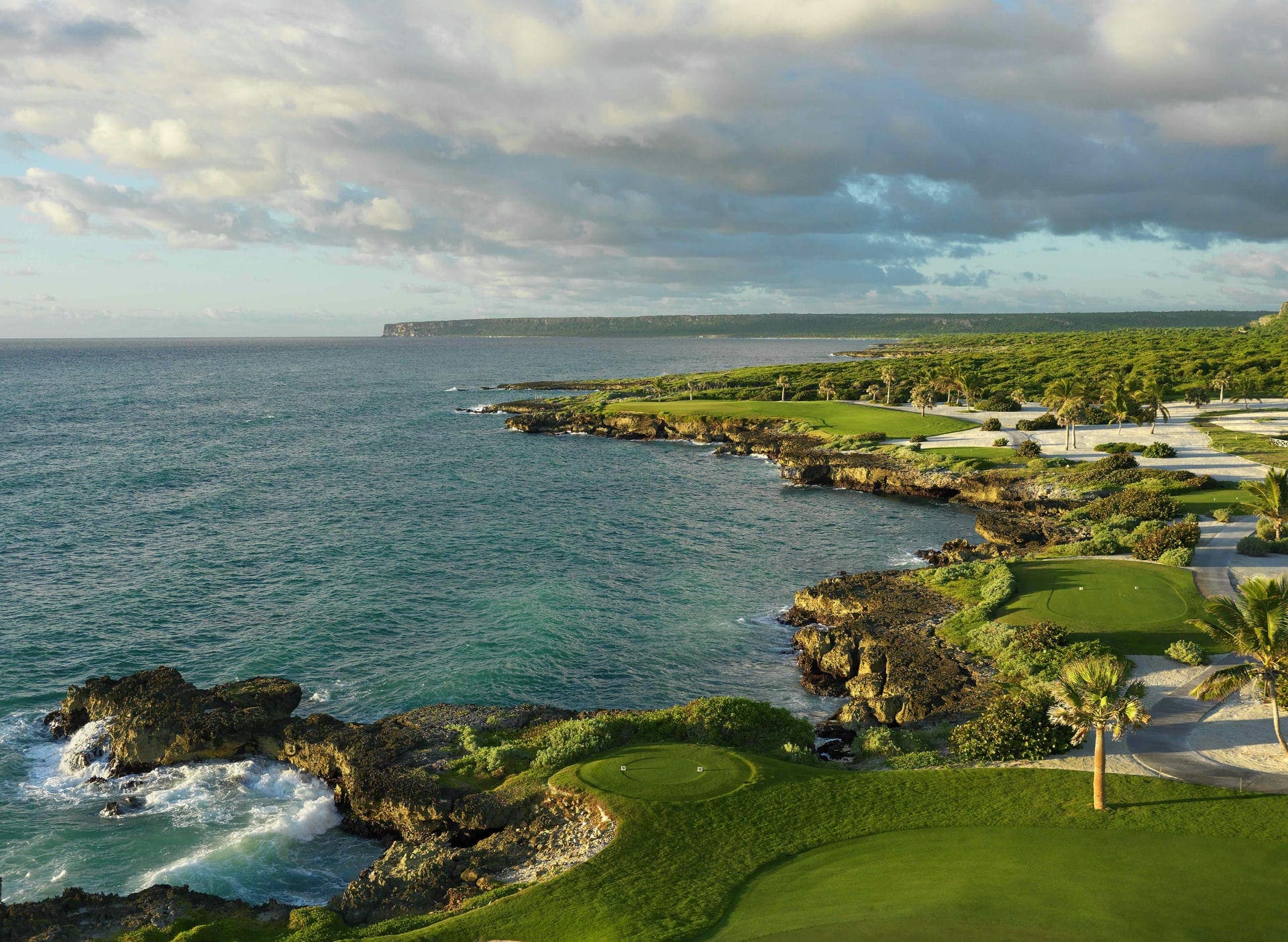 The 13th hole at Punta Espada Golf Club, its green set on a low rock shelf above the sea.