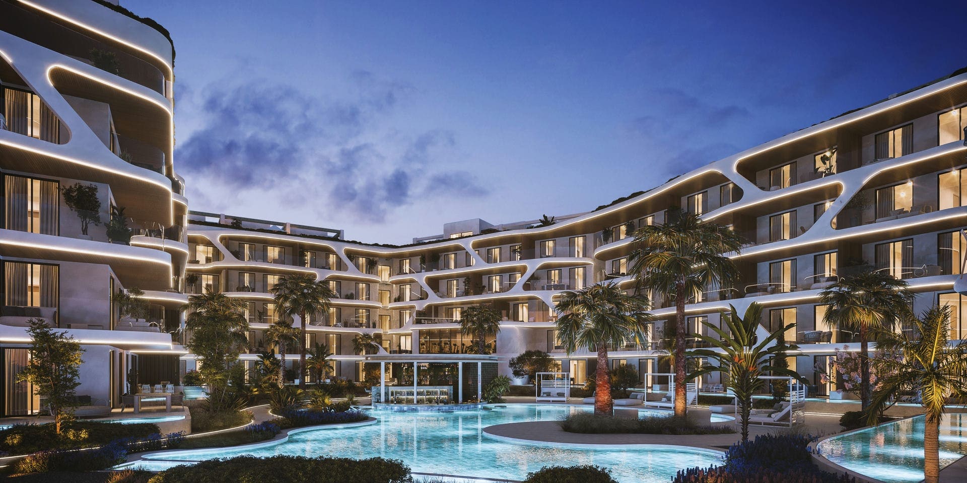 The development at dusk, both residence wings lit above the pool courtyard.