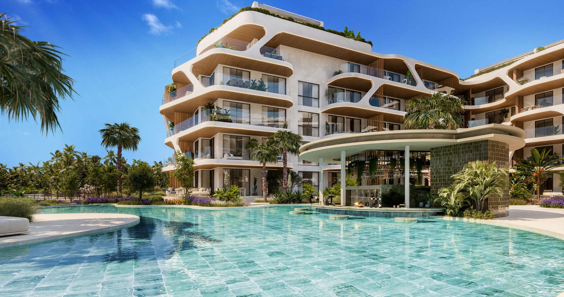 The resort pool with the poolside bar set into the base of the residences, shaded by palms.